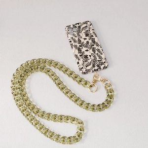 Gros plan sur la chaîne en résine vert olive et la coque de téléphone à motif floral