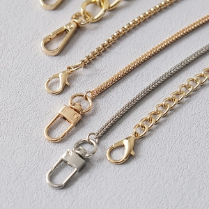 Detailed close-up of metallic gold and silver bag chain straps with polished lobster clasps
