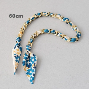 Détail d'une bandoulière chaîne en métal doré et foulard en soie de 60 cm