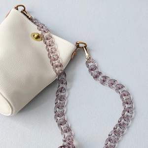 Close-up of translucent purple acrylic resin chain on a white leather bucket bag