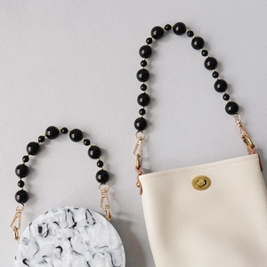 Detail of beaded acrylic handles on marble texture round bag and beige leather square purse
