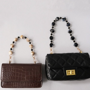 Detail of acrylic bead handle on crocodile brown and quilted black handbags
