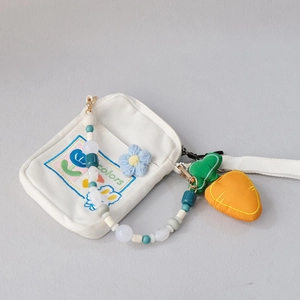 Detail of white canvas bag with colorful acrylic beads strap and carrot charm