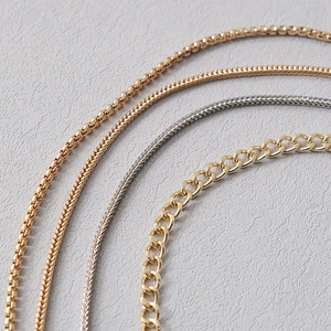 Detailed close-up of gold and silver wheat and curb chains for bags and jewelry