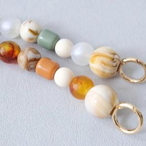 Détail de chaînes de perles colorées en résine et acrylique avec anneaux dorés en métal