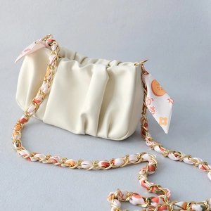 Detail of cream pleated cloud bag with gold chain and fruit print silk scarf strap