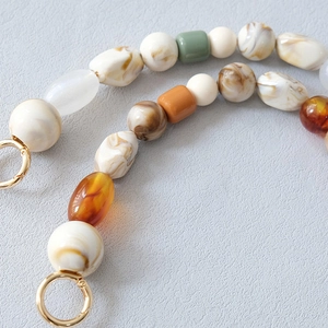 Détail macro d'une chaîne de perles en résine avec motifs marbre et fermoirs dorés