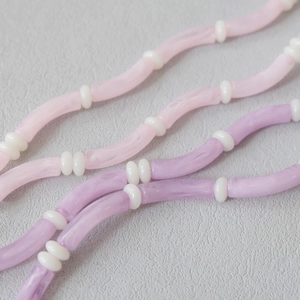 Detailed macro view of pink and purple acrylic tube beads with marble texture and spacers