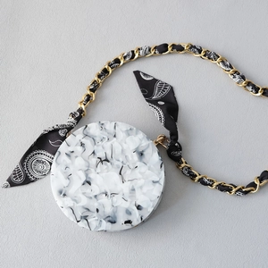 Detail view of round marble resin handbag with gold chain and paisley silk scarf strap