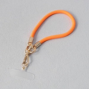 Détail de la lanière de téléphone tressée orange vif avec fermoir mousqueton doré et onglet