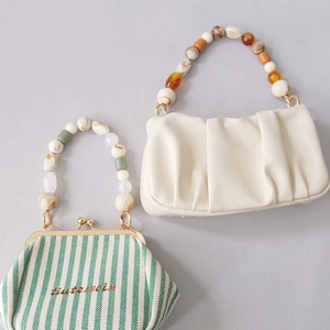 Détail de poignées en perles de résine colorées sur sacs en cuir plissé et toile rayée