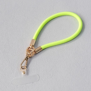 Détail du cordon de téléphone en nylon tressé vert fluo avec attaches dorées et onglet