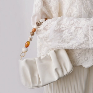 Détail d'un sac nuage plissé blanc crème avec une poignée en perles colorées faite main