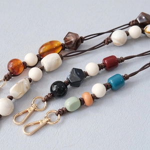 Close-up of handmade acrylic beads on woven cord with a gold lobster clasp attachment