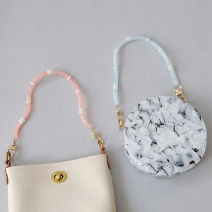 Detail of gradient acrylic bead handles on stylish crossbody bags with gold lobster clasps