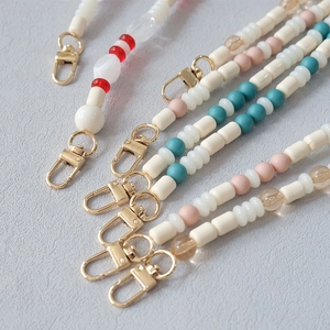 Detailed macro view of colorful acrylic beaded straps with golden lobster clasps for bags