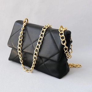 Detail of black quilted leather shoulder bag with stylish chunky gold metal chain strap