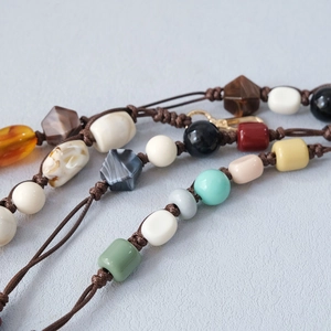 Detailed macro view of colorful acrylic beads and gold lobster clasp on hand-woven strap