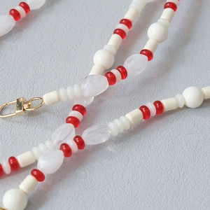 Detail of red and white acrylic beads on a phone strap with gold lobster clasp