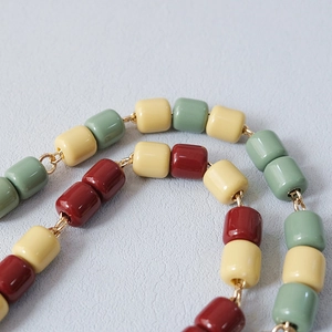 Close-up of handmade acrylic resin bead chain with colorful cylinders and gold metal links