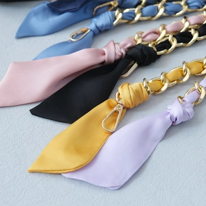 Close-up of golden metal chain straps with colorful silk scarves for handbags