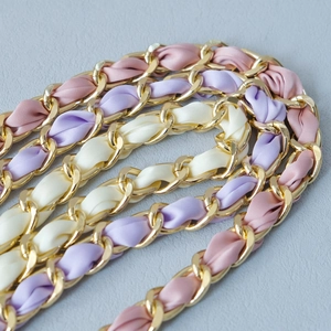 Detail of luxury gold metal chain intertwined with pink and lilac silk scarves