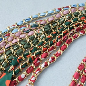 Dettaglio di varie catene per borse dorate intrecciate con nastri di seta multicolori