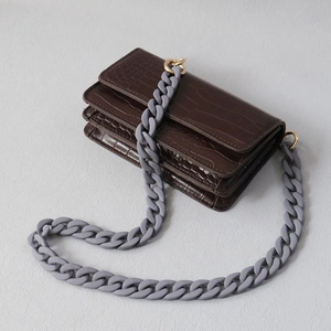 Detail view of coffee crocodile texture handbag with grey matte resin chain strap