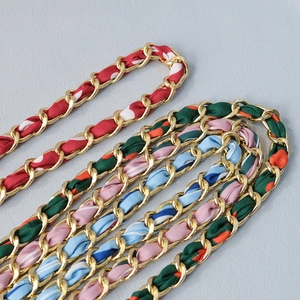 Dettaglio di catene in metallo dorato intrecciate con foulard di seta colorati per borse
