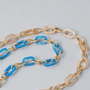 Detail of acrylic links with cloud marble texture and gold metal rings in blue and beige