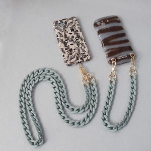 Macro detail of matte grey-blue acrylic chain link with gold metal clasps for phone cases