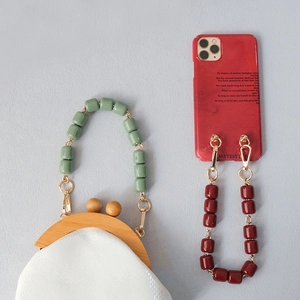 Detail view of colorful resin bead straps on a beaded handbag and marble phone case