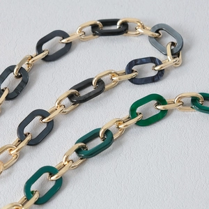 Detail of stylish acrylic and gold metal link chain for bags with marble texture