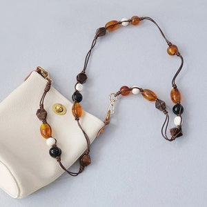 Detailed close-up of acrylic beaded shoulder strap and woven rope on a cream bucket bag