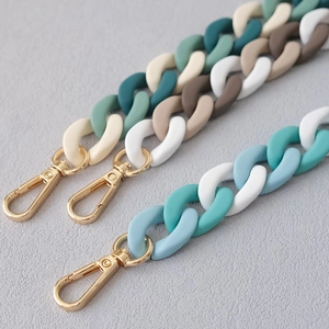 Detailed macro view of matte resin link chains with gold metal lobster clasps for bags