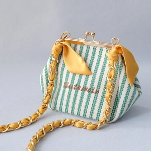 Detail of green striped frame bag with yellow bunny ears and golden chain strap