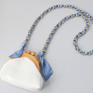 Elegant off-white crossbody bag with vintage wooden clasp and silk ribbon chain strap
