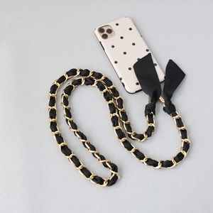 Detail of crossbody gold metal chain woven with black ribbon and silk bow accents