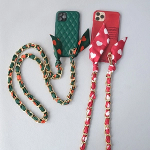 Custodie per telefoni verdi e rosse con tracolla a catena dorata e nastro floreale