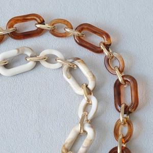 Close-up of amber and marble acrylic chunky bag chains with gold metal connecting rings
