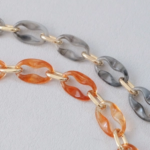 Detail of gray marble and amber acrylic resin chain links with gold metal rings