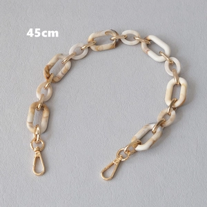 Detail showing 45cm acrylic bag chain with cream and marble links and gold lobster clasps