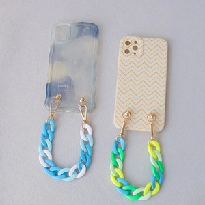 Detailed view of resin fishbone chain straps and aesthetic phone cases in pastel colors