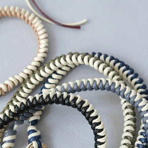 Close-up of woven two-tone wax rope chain with golden metal rings for handbags