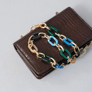 Detail of croc-embossed brown leather bag with colorful acrylic and gold metal chain