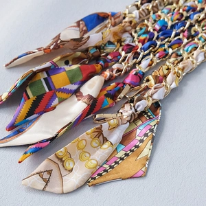Detailed close-up of golden metal chains interwoven with colorful patterned silk scarves