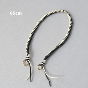 Close-up of a 65cm black and white braided wax rope strap with gold rings and tassels