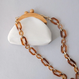 Detail view of cream snake pattern purse with wooden kiss-lock and amber acrylic chain