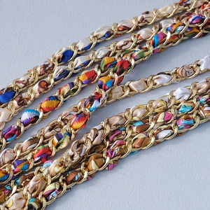 Macro detail of golden metal chain woven with colorful leopard print silk scarf