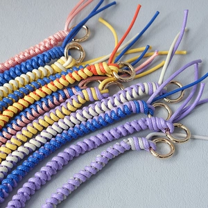 Close-up of colorful braided rope bag chains with elegant gold metal ring clasps